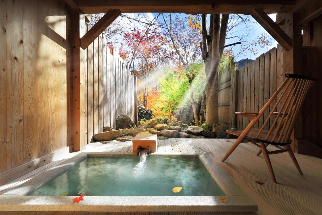 Wooden outdoor onsen at Syoubun Gunma Sunlit outdoor wooden onsen tub with stone garden and maple leaves at Syoubun, Gunma, Kantō