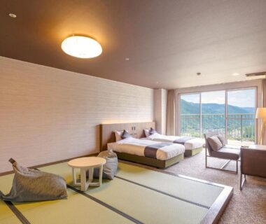 Spacious tatami room with twin beds, low table, lounge chairs and mountain view at TAOYA Gero
