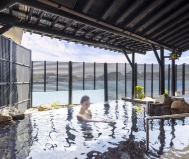 Guest relaxing in a sheltered onsen pool with wooden roof and sea views at TAOYA Nachikatsuura, Wakayama