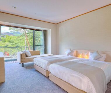 Bright twin room with two beds, seating area and glass balcony opening to lush greenery at TAOYA Nasu Shiobara, Tochigi