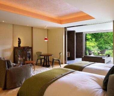 Twin beds and seating area opening onto lush garden terrace in Hakone, Kanagawa ryokan