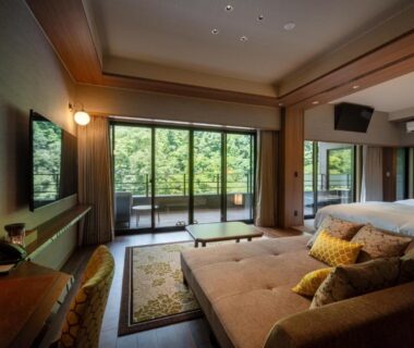 Spacious tatami room with low table, sofa and balcony overlooking greenery at THE YUKAWA Ichijoh Branch Miyagi