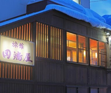 Snow-covered wooden facade and lit windows at Tabataya in Niigata