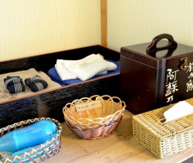 Folded yukata, slippers and woven baskets at a ryokan entrance, Tabinoyado Asonoyu, Kumamoto
