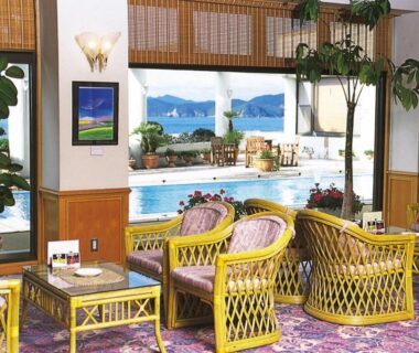 Wicker seating and tables in lounge with bay view and plants, Tabinoyado Ushionoakari Geiboso, Mie