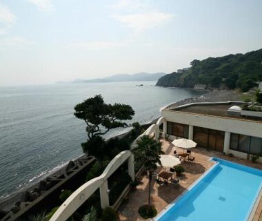 Outdoor pool and umbrellas overlooking rocky coastline at Tabinoyado Ushionoakari Geiboso in Mie, Kansai