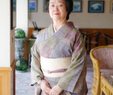 Woman in kimono standing in ryokan lobby with wicker chairs and framed artwork, Tabinoyado Ushionoakari Geiboso, Mie