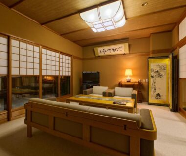 Traditional tatami room with low table, sofa, shoji screens, tokonoma alcove and soft lighting at Tabist Chikuba Shinyotei Hokkaidō