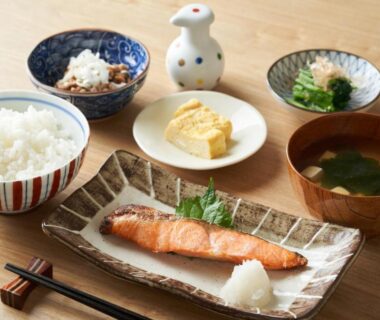 Traditional Japanese breakfast set with grilled salmon, rice, miso soup, tamagoyaki and small side dishes on wooden table