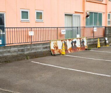 Empty parking spaces by Tabist Hotel Seishokan exterior in Shizuoka with traffic cones and rusted metal boards