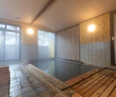 Steaming indoor onsen bath with wooden edging at Tabist Kazeyuki in Gifu, Chūbu