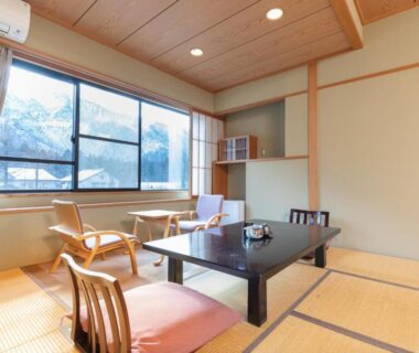 Tatami room with low table, floor chairs and mountain view at Tabist Kazeyuki in Gifu
