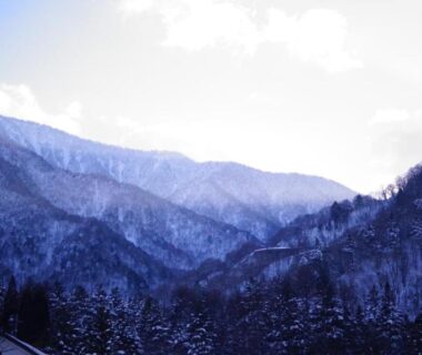 Snow-covered mountain valley with forested slopes near Tabist Kazeyuki in Gifu, Chūbu