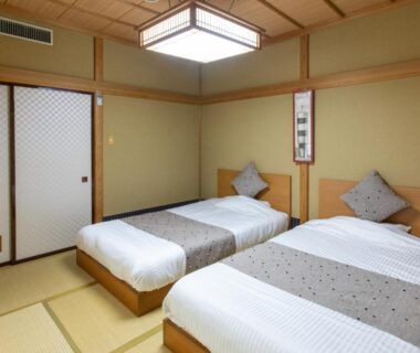 Tatami room with twin beds and shoji screens at Tabist Koboshi no Yu Senshintei Aizu Yunokamionsen, Fukushima