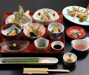 Assorted Japanese dishes on lacquer tray with tempura, grilled fish, small bowls and chopsticks in Aizu, Fukushima