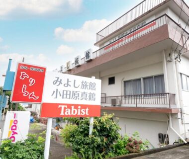 Entrance sign and white multi-story ryokan building with balconies in Kanagawa prefecture