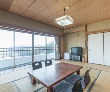 Tatami room with low table and balcony at Tabist Miyoshi Ryokan in Kanagawa