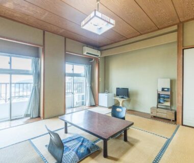 Traditional tatami room with low table, floor cushions, shoji screens and balcony at Tabist Miyoshi Ryokan in Kanagawa