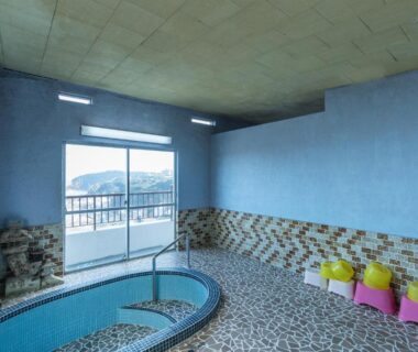 Indoor tiled bath with small wash stools and balcony mountain view at Tabist Miyoshi Ryokan, Manazuru, Kanagawa