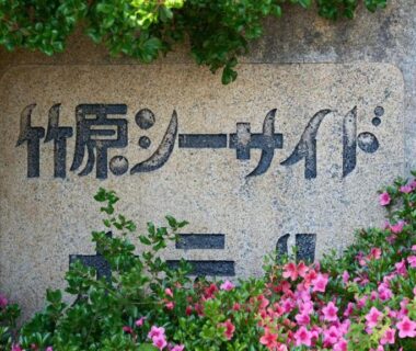 Stone entrance sign reading Takehara Seaside surrounded by pink flowers and greenery