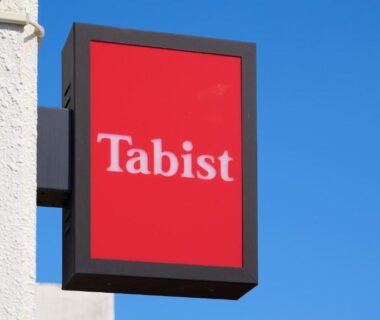 Red Tabist sign mounted on exterior wall against clear blue sky at Takehara Seaside ryokan in Hiroshima