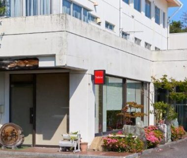 White ryokan entrance with potted plants and driveway at Tabist Setouchinoyado Takehara Seaside in Hiroshima