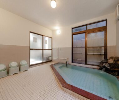 Indoor tiled onsen bath with stools and stone water feature, Tabist Yamaga Onsen Yuyado Izumi, Kumamoto Kyushu