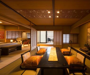 Traditional tatami room with low dining table, floor cushions, shoji screens and sleeping area at Tachibana Shikitei, Ishikawa