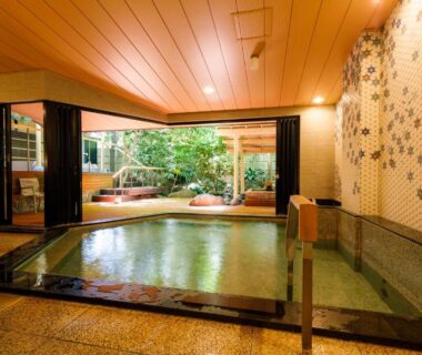 Indoor communal bath with tiled wall, wooden ceiling and garden view at Tachibana Shikitei, Ishikawa
