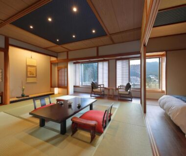 Spacious tatami room with low table, zabuton seating, twin beds and balcony chairs in Tachibanaya, Yamagata