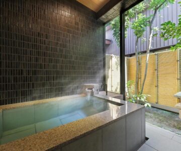 Tiled indoor onsen bath with courtyard garden at Tachibanaya in Yamagata