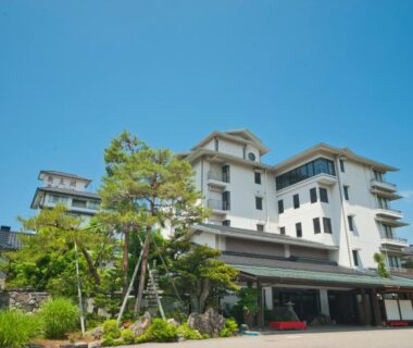 Multi-story ryokan exterior with landscaped entrance and trees at Tagawa Ryusenkaku in Ishikawa, Chubu