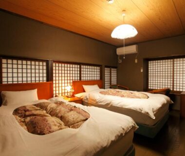 Twin beds in Japanese-style room with shoji screens and wooden ceiling at Tagoto, Fukushima