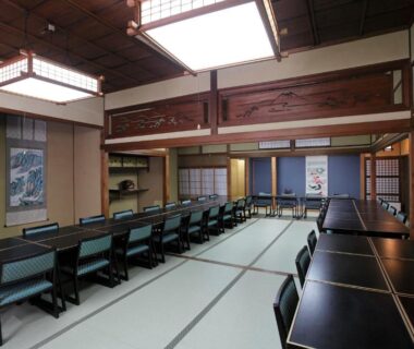 Long tatami dining room with black tables, chairs, shoji screens and wooden beams at Tagoto, Fukushima