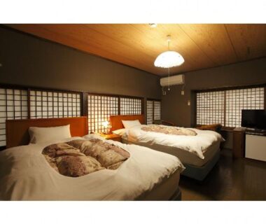 Warm twin bedroom with shoji screens, wooden ceiling and bedside lamps at Tagoto ryokan in Fukushima, Tōhoku
