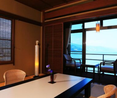 Tatami room with low table, shoji screens and balcony overlooking coastal waters in Shizuoka