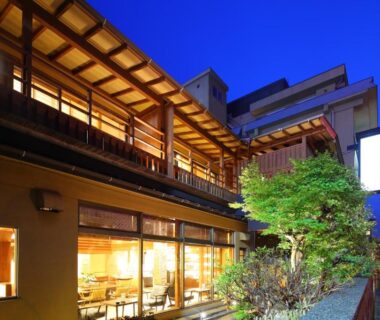 Night view of Taiseikan exterior with illuminated wooden facade, dining windows and small landscaped garden