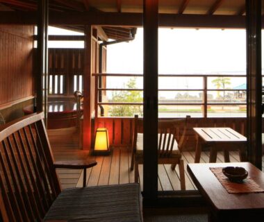 Interior veranda with wooden chairs and low table overlooking outdoor railing at Taiseikan, Shizuoka