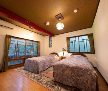 Twin beds on wooden floor with wood-framed translucent windows, Taisho Yufu no Hana, Ōita