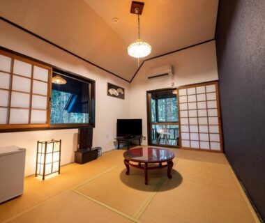 Traditional tatami room with low round table, shoji screens, TV and sliding doors at Taisho Yufu no Hana, Ōita