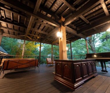 Open wooden terrace with piano and seating at Taisho Yufu no Hana, Ōita, Kyūshū, Japan