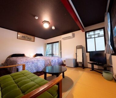 Twin beds, tatami flooring and seating area at Taisho Yufu no Hana in Ōita, Kyūshū