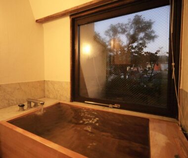 Wooden indoor soaking tub beside window overlooking trees at Taishoya in Saga, Kyūshū