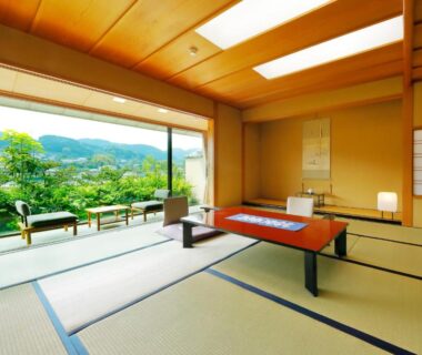 Spacious tatami room with low table, sliding panels and window seating overlooking green hillside garden