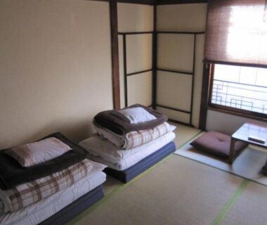 Traditional tatami room with folded futons, low table and shoji screens at Taito Ryokan in Tokyo
