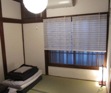 Tatami room with stacked futons and bamboo blinds at Taito Ryokan in Tokyo, Kantō