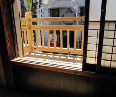 Open shoji screens and wooden balcony railing at Taito Ryokan overlooking a Tokyo street