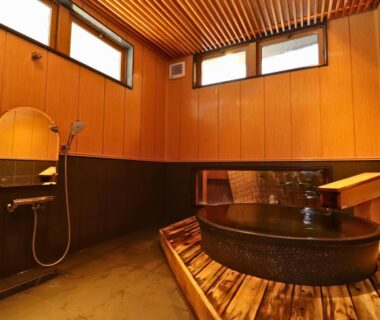 Indoor soaking tub with wooden platform and shower area at Taiyokan in Gunma, Kanto