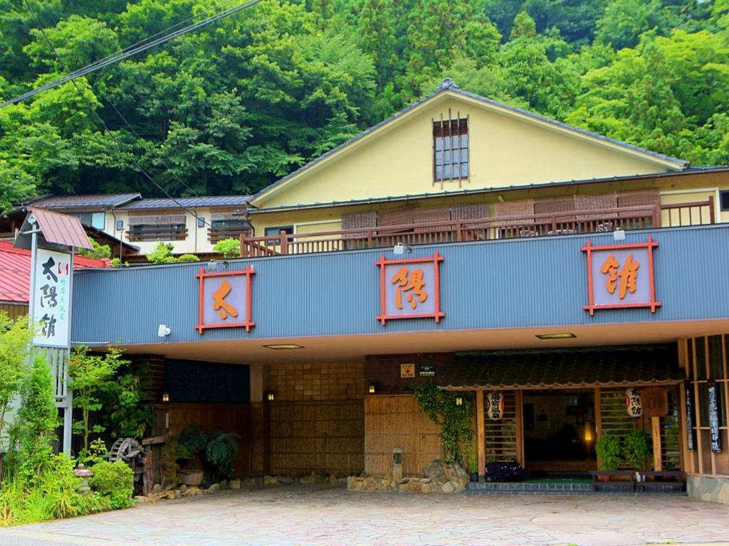 Traditional ryokan exterior Taiyokan Gunma Yellow two-story ryokan facade with entrance and mountain backdrop at Taiyokan in Gunma, Kantō