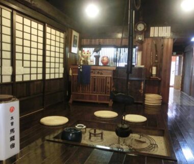 Interior with irori hearth, low kettles, round floor cushions and shoji screens at Tajimaya in Gifu, Chūbu